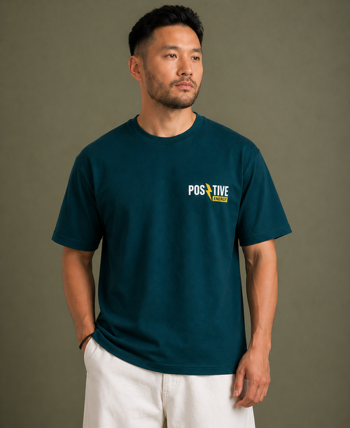 Man wearing a teal t-shirt with a 'Positive' logo on a brown background